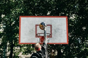 man dunking a basketball on outdoor court