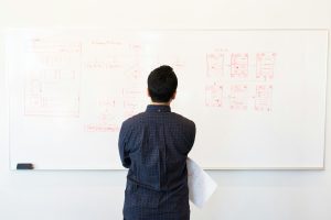 man looking at a whiteboard with graphs on it
