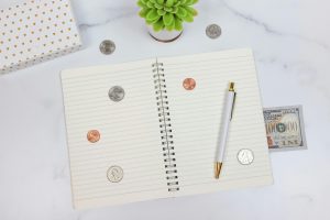 marble desk with pen, notebook, million dollar bill and pennies