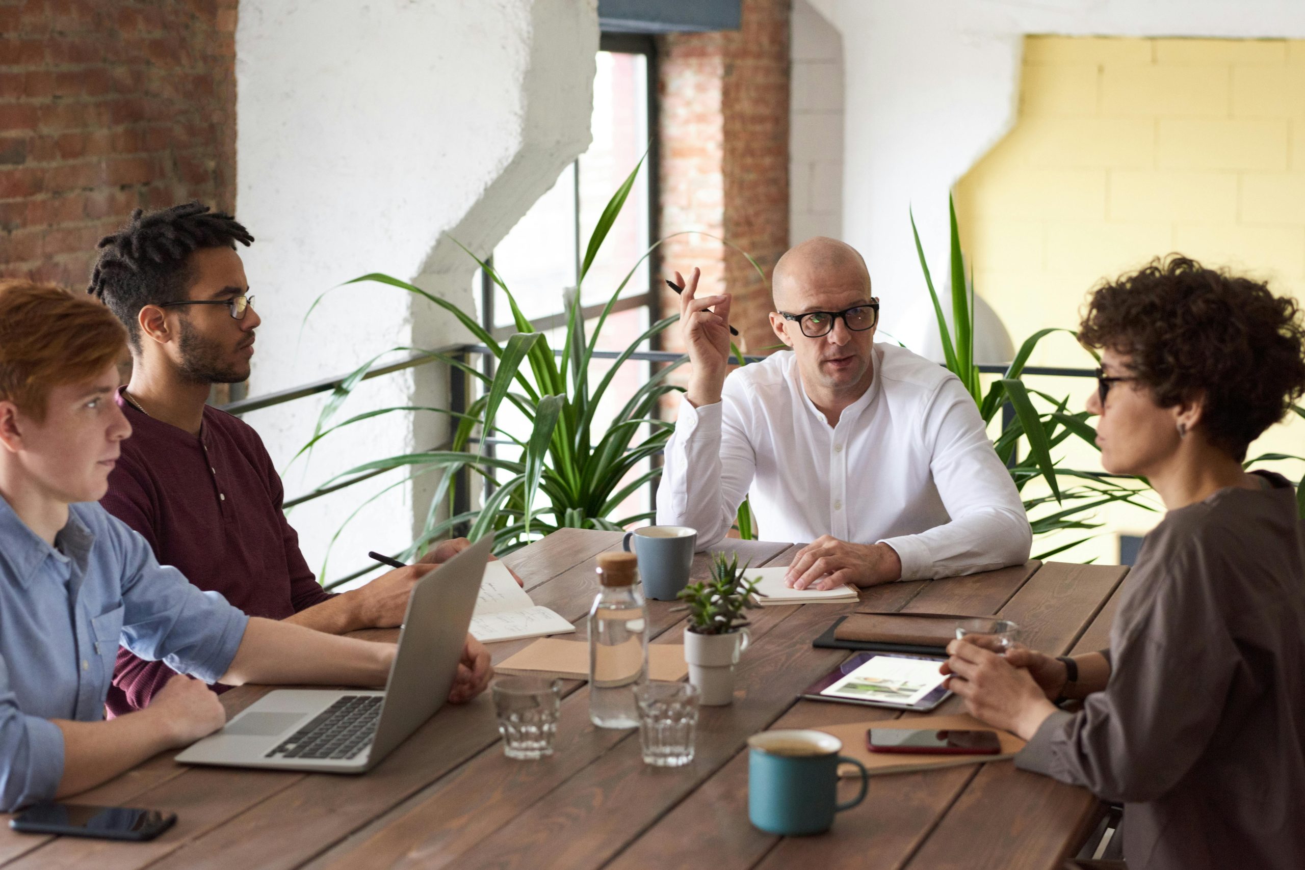 people with laptops around wooden table