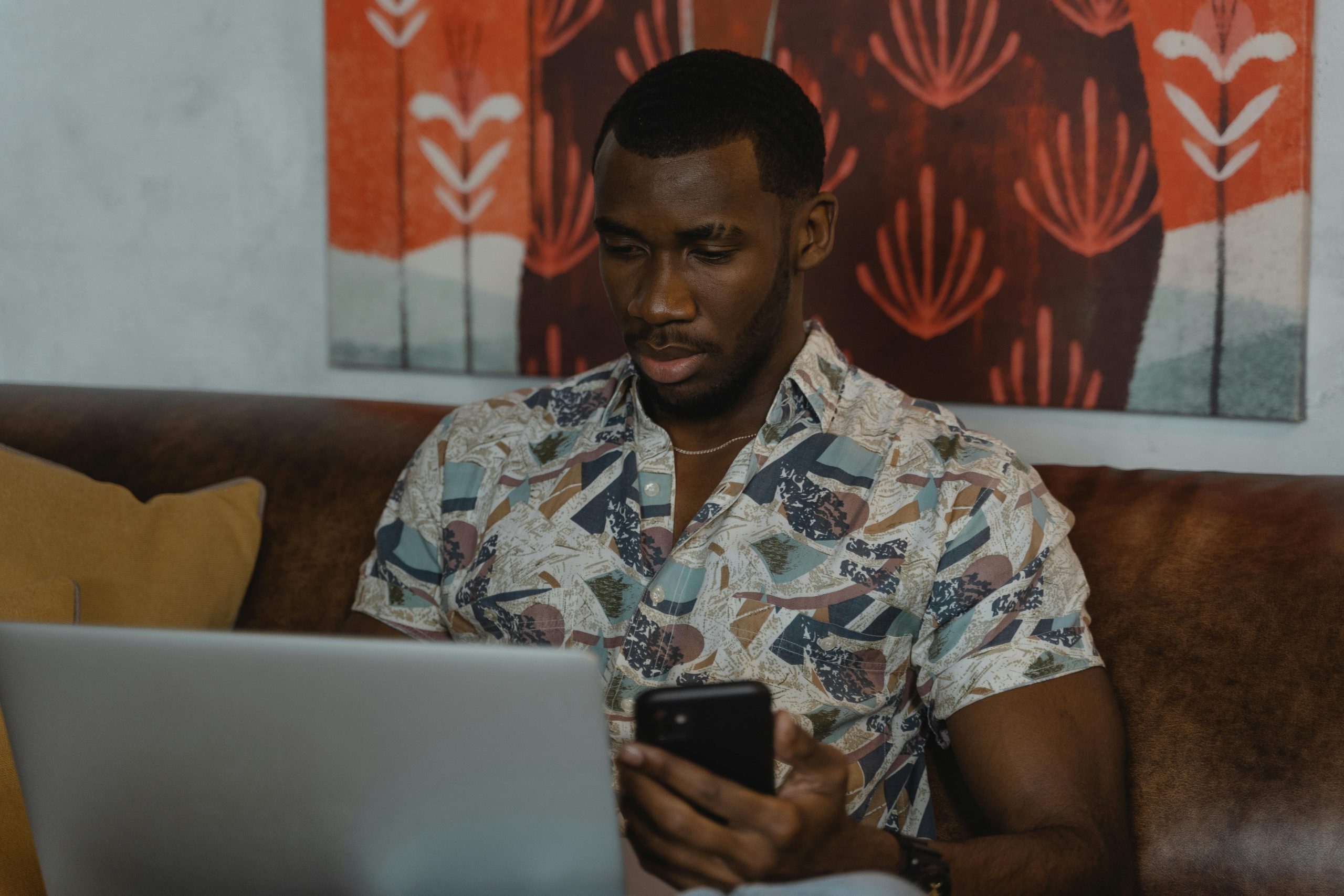 man on couch with laptop and phone
