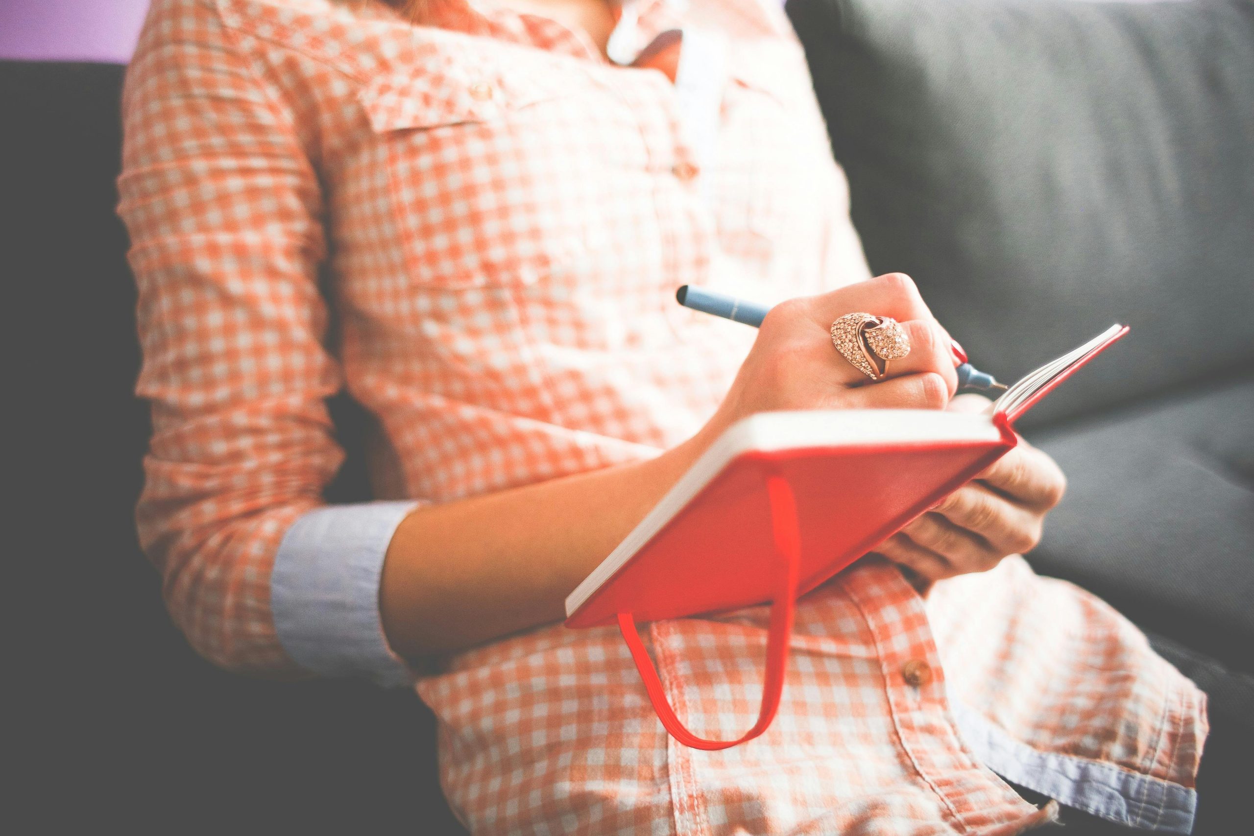 woman in red checkered dress writing in red diary