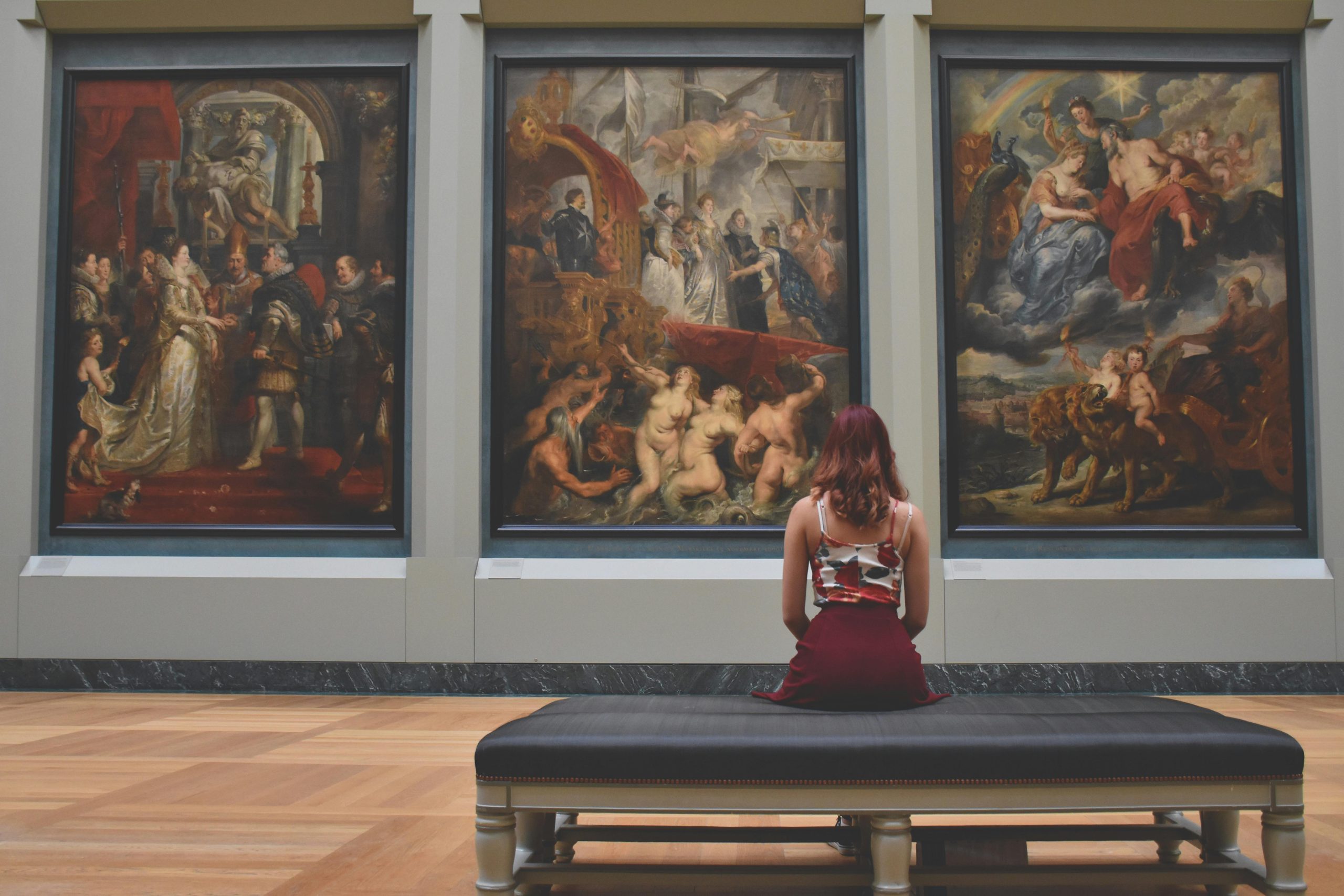 woman sitting in front of gallery paintings