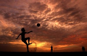 soccer kick against sunset and clouds