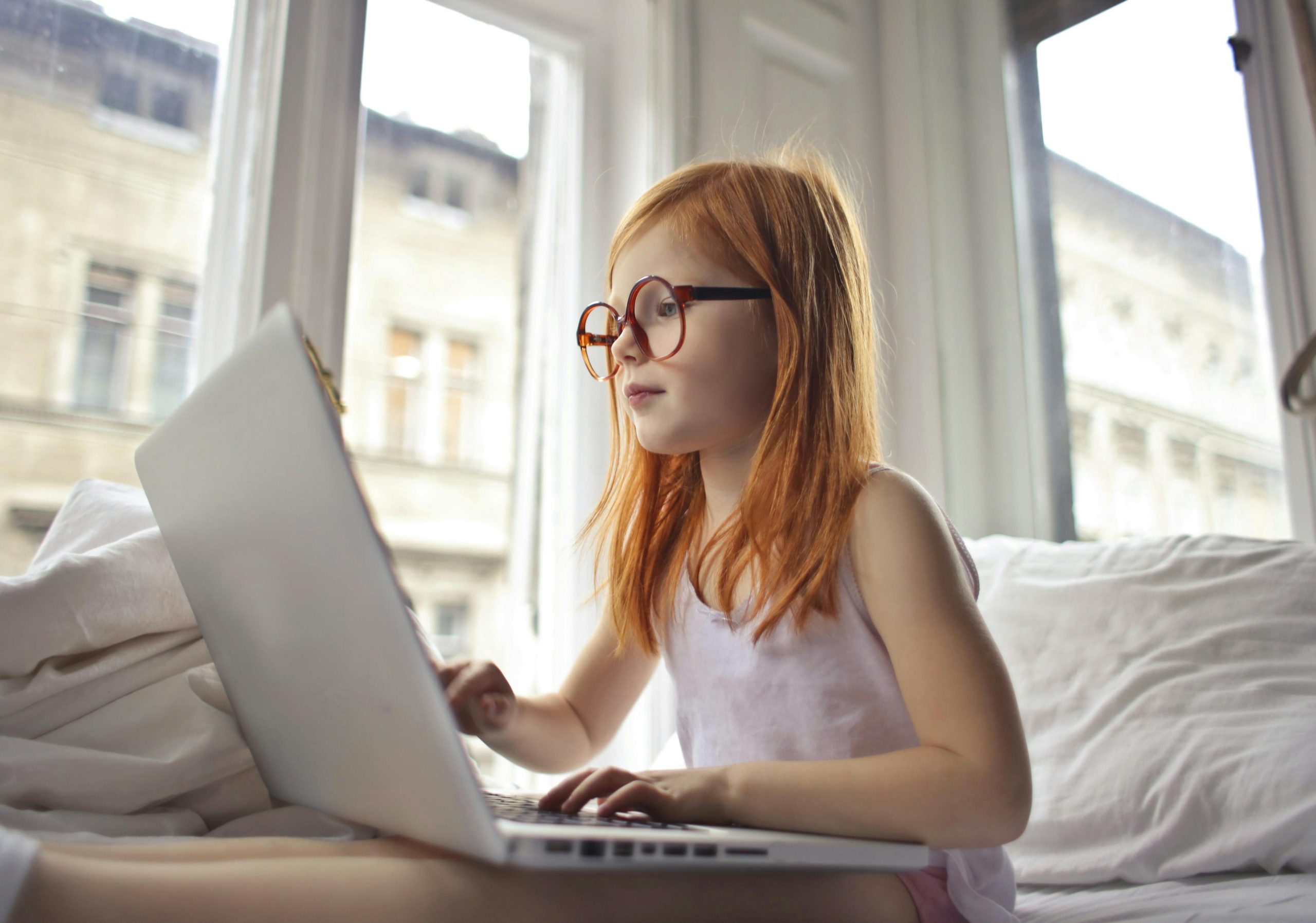 red haired girl with glasses searching on laptop