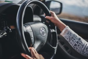 close up of woman's hands on steering wheel driving a car
