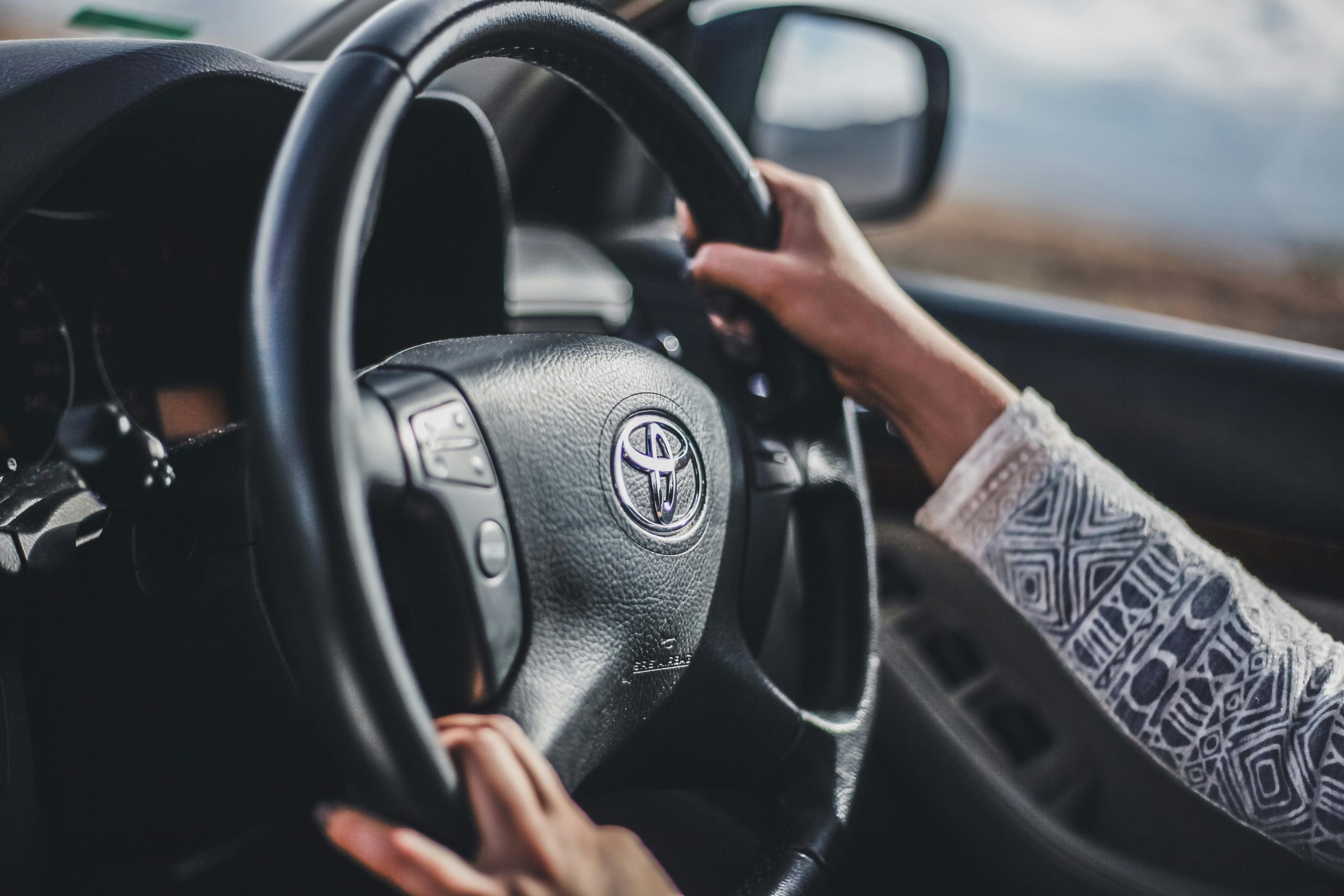 close up of woman's hands on steering wheel driving a car